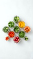 Fresh vegetables stored in glass jars on white background for meal prep and healthy eating lifestyle.