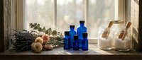 Rustic wooden windowsill with blue glass bottles, dried lavender bundles, and glass jars in warm natural sunlight for aromatherapy and herbal medicine.