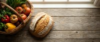 Fresh organic vegetables and artisan bread on rustic wooden table with natural lighting for healthy cooking and farm-to-table dining concepts.