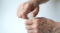 Senior man with wrinkled hands holding blank white ring box, isolated on white background. Suitable for engagement, marriage proposal, jewelry, and lifestyle concepts.