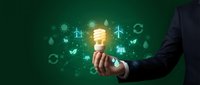 Businessman holding glowing energy-saving bulb with green renewable energy icons on dark background, symbolizing eco innovation.