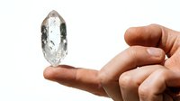 Clear quartz crystal specimen held in hand, isolated on white background. Raw mineral stone for jewelry design, healing practices, and educational purposes.