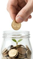 Hand dropping gold coin into glass jar containing seedling and stacked coins, symbolizing financial growth, investment returns, and wealth accumulation for business and savings concepts.