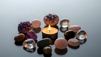 Healing crystals and gemstones arranged around glowing candle for meditation, spiritual wellness, chakra balancing and holistic therapy practices.
