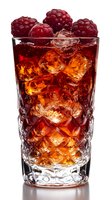Fresh raspberries garnish a crystal glass filled with dark red cocktail and ice cubes, backlit to showcase amber liquid and intricate glass pattern details.