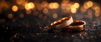 Golden wedding rings on dark textured surface with magical bokeh lights creating romantic atmosphere. Elegant jewelry symbolizing eternal love and marriage.