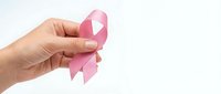 Female hand holding pink ribbon symbol for breast cancer awareness campaign on white background isolated for medical and healthcare design.