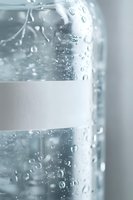 Condensation droplets on cold glass surface with water drops running down. Refreshing close-up view showing pure mineral water bottle texture in soft light.