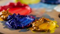 Vibrant oil paint colors mixed on artist palette with brush strokes showing red, blue and yellow pigments for creative artwork and painting projects.