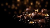 Chocolate heart-shaped candies with gold leaf and cocoa powder on dark background, perfect for Valentine's Day, wedding, and luxury confectionery marketing.