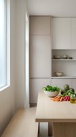 Modern minimalist kitchen interior with fresh vegetables on wooden counter and built-in storage cabinets for contemporary home design and cooking.