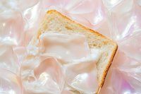 A slice of white toast with cream spread on a shimmery iridescent plastic wrap background, soft pastel pink tones, flat lay food styling.