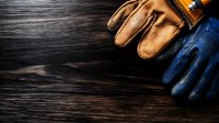 Protective leather and rubber work gloves on dark wooden background with copy space, overhead view for construction and safety equipment concepts.