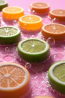 Fresh citrus slices of lime and orange on pink background with water drops and bubbles, macro shot with selective focus for food and beverage design.