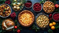 Festive holiday table with homemade pies, fresh berries, citrus fruits and roasted turkey on dark background. Traditional celebration feast spread.