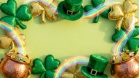 Flat lay St. Patrick's Day celebration with gold coins, green shamrocks, leprechaun hats, and rainbow ribbons on yellow background for holiday marketing and festive designs.