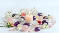 Healing crystals amethyst rose quartz with burning candle and flowers for meditation wellness spa relaxation energy cleansing ritual ceremony.