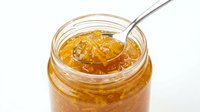 Homemade marmalade or jam in glass jar with spoon, isolated on white background for food packaging, recipe blogs, and culinary design projects.