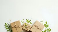 Kraft paper gift boxes tied with twine surrounded by fresh green leaves and foliage on white background, suitable for eco-friendly packaging, sustainable gifting, and natural product promotion.