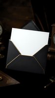 Elegant black envelope with gold trim containing blank white letter or card for luxury correspondence and formal invitations.
