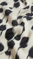 Cream and black brushstroke pattern on soft fabric with natural folds and texture, suitable for textile design, fashion backgrounds, and apparel printing projects.