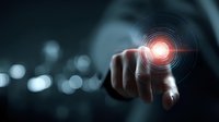 Businessman finger touching glowing digital interface with red circular target on dark background, representing futuristic technology and innovation.