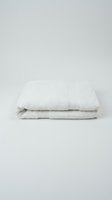 Folded white cotton bath towel isolated on light background, showcasing soft terry texture and clean hotel-style presentation for spa and home decor.