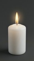 White pillar candle burning with bright flame against dark background creating warm atmospheric lighting for relaxation and meditation.