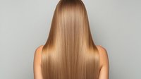 Long straight honey blonde hair from back view on young woman with healthy, shiny, smooth texture against light gray background. Professional salon result.
