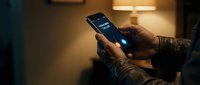 Person using smartphone with glowing screen in cozy evening home setting with warm ambient lighting for digital communication and technology concepts.