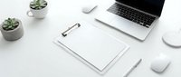Clean minimalist white workspace with laptop, clipboard, succulents and office supplies arranged on desk for modern business productivity and organization.