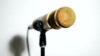 Gold condenser microphone with black stand and cable on white background, ready for recording, podcasting, voiceover, and music production projects.