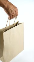 Senior hand holding brown paper shopping bags on white background for retail and consumer concepts.