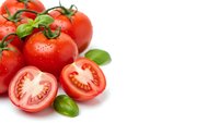 Fresh red tomatoes with green basil leaves on white background, some cut in half showing seeds and flesh, isolated for cooking and food design.