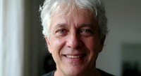 Senior Caucasian man with gray hair smiling warmly at camera in bright indoor setting for lifestyle and wellness content.