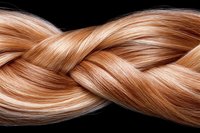 Shiny strawberry blonde hair braid on black background showcases smooth, healthy strands with natural highlights and texture for beauty and haircare concepts.