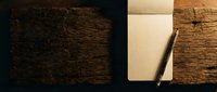 Overhead view of aged wooden surface with blank cream notebook and pencil, suitable for stationery, workspace, and creative projects.