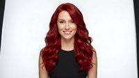 Young Caucasian woman with long wavy red hair smiling at camera wearing black top against white background isolated for design use.