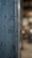 Weathered blue painted metal surface with peeling paint and rust spots showing age and deterioration with blurred urban background for industrial design projects.