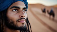 Young Middle Eastern man in traditional blue turban looking into distance against desert landscape with camel silhouettes, capturing cultural heritage and wanderlust spirit.