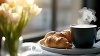 Fresh baked croissants and steaming hot coffee cup on white plate near window with morning light and white tulips, cozy breakfast atmosphere.