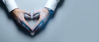 Business professional hands forming heart shape gesture showing care compassion and corporate social responsibility in workplace environment.