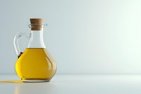 Glass carafe with golden olive oil and cork stopper on light background with copy space, minimalist food photography composition.