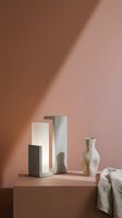 Minimalist ceramic vases and geometric sculptural forms arranged on neutral platform with warm lighting, suitable for home decor, interior design, and product showcase applications.