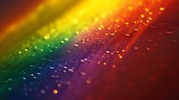 Vibrant rainbow spectrum with water droplets creating bokeh effect on colorful gradient background, from yellow through green to deep red for abstract designs.
