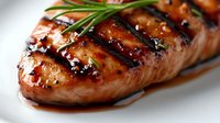 Grilled salmon fillet with caramelized glaze and fresh rosemary garnish on white plate. Restaurant quality seafood dish for culinary and food photography projects.