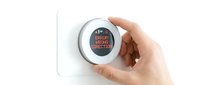Modern smart home thermostat with digital display showing error message being adjusted by hand on white wall for temperature control and energy efficiency.