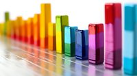 Colorful ascending bar graph elements arranged in rainbow spectrum order on white surface with selective focus and depth of field effect.
