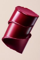 Burgundy lipstick sample cut diagonally showing creamy texture and rich color against neutral background, demonstrating luxurious cosmetic product quality.