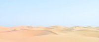 Vast desert landscape with rolling sand dunes under clear sky, suitable for travel, nature, and background design projects.